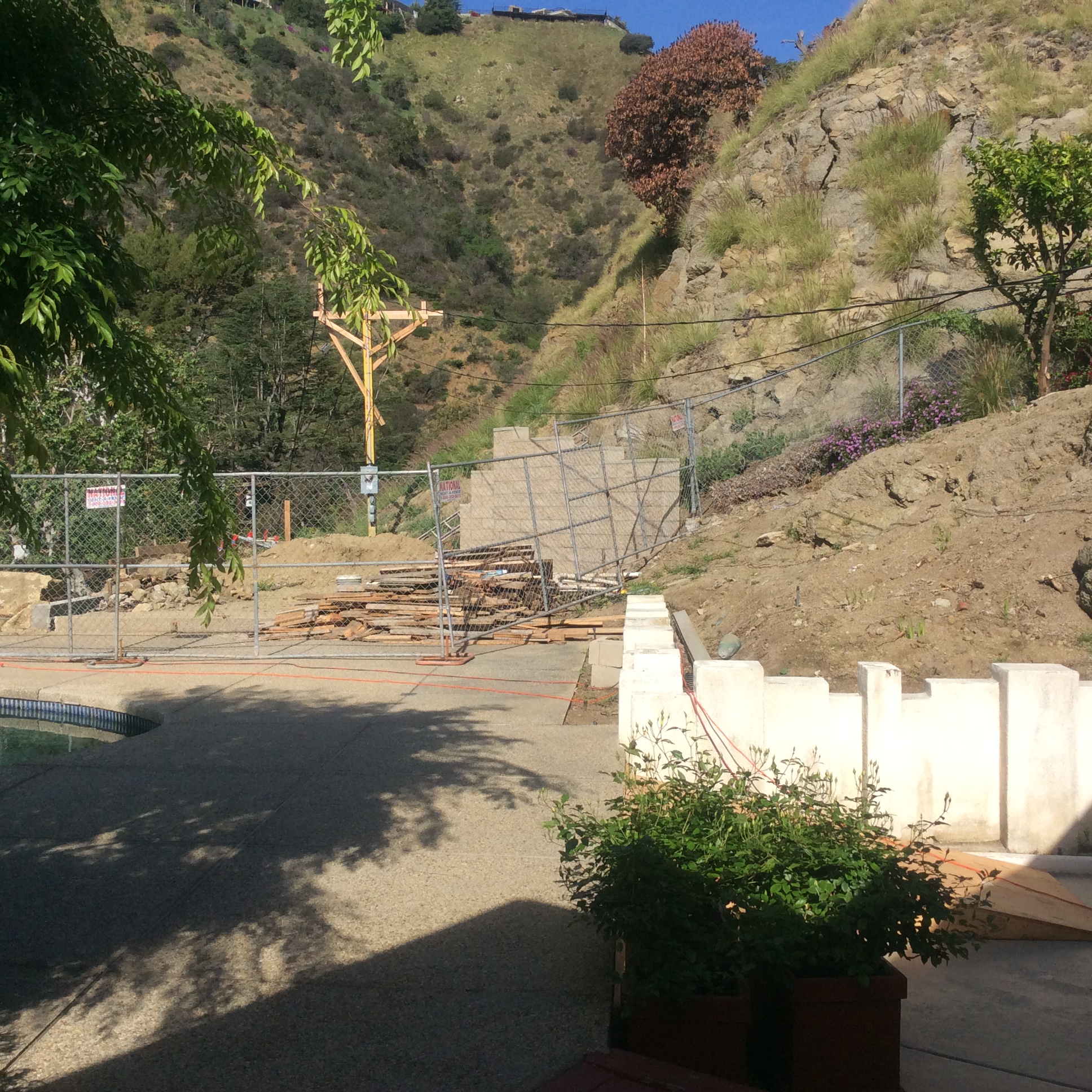 The same site mid-construction, with temporary fencing, rough grading, and retaining forms