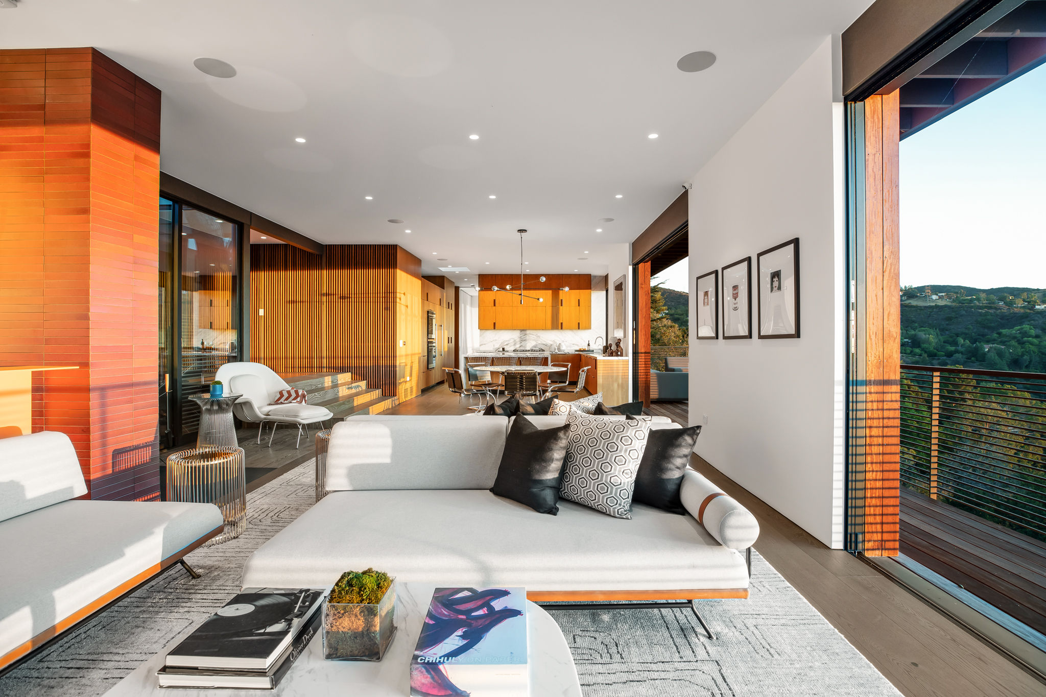 Westridge Residence at sunset: living room open to the deck, brick hearth and skyline beyond